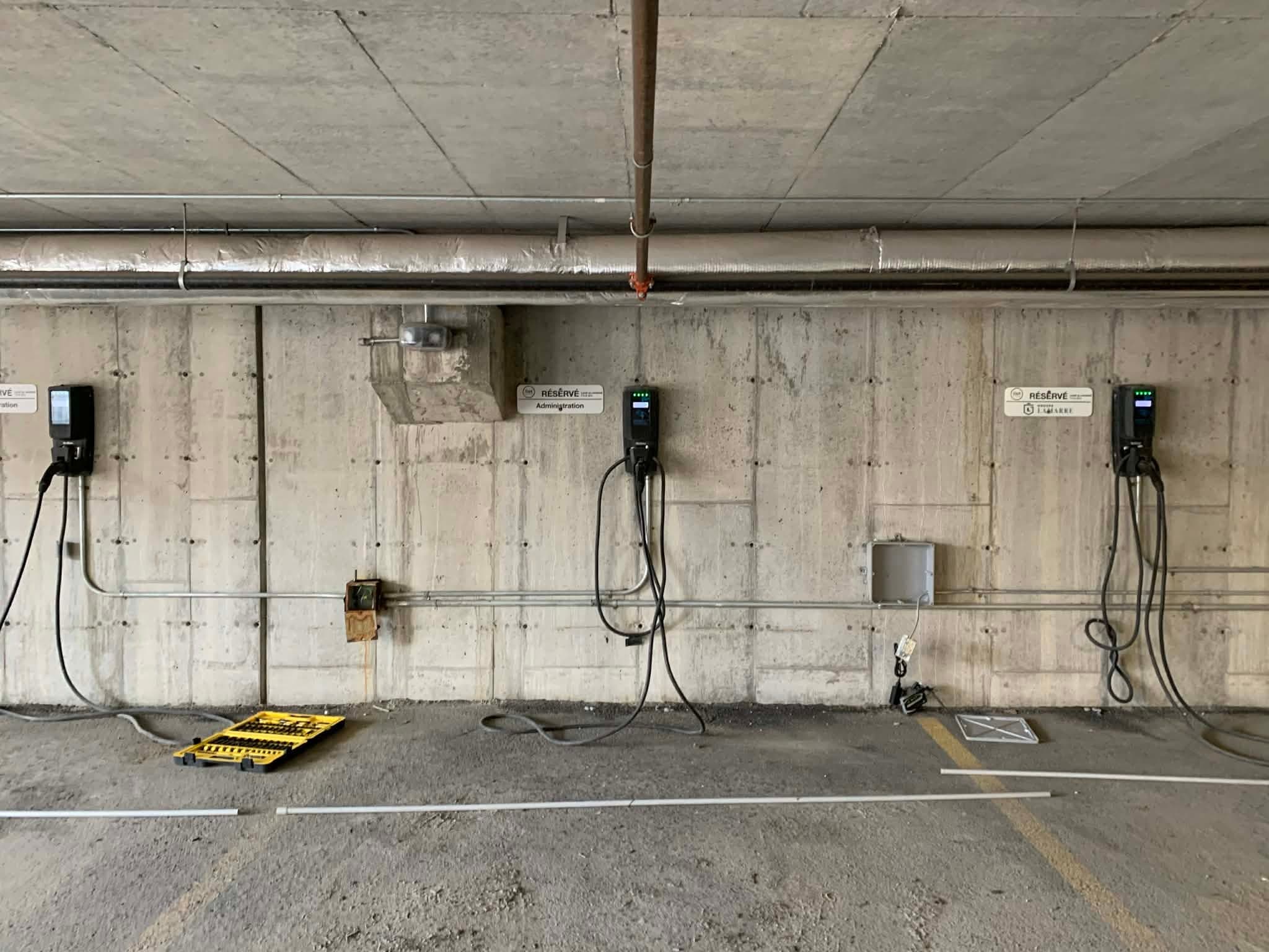 Three chargers on the concrete wall of an underground parking