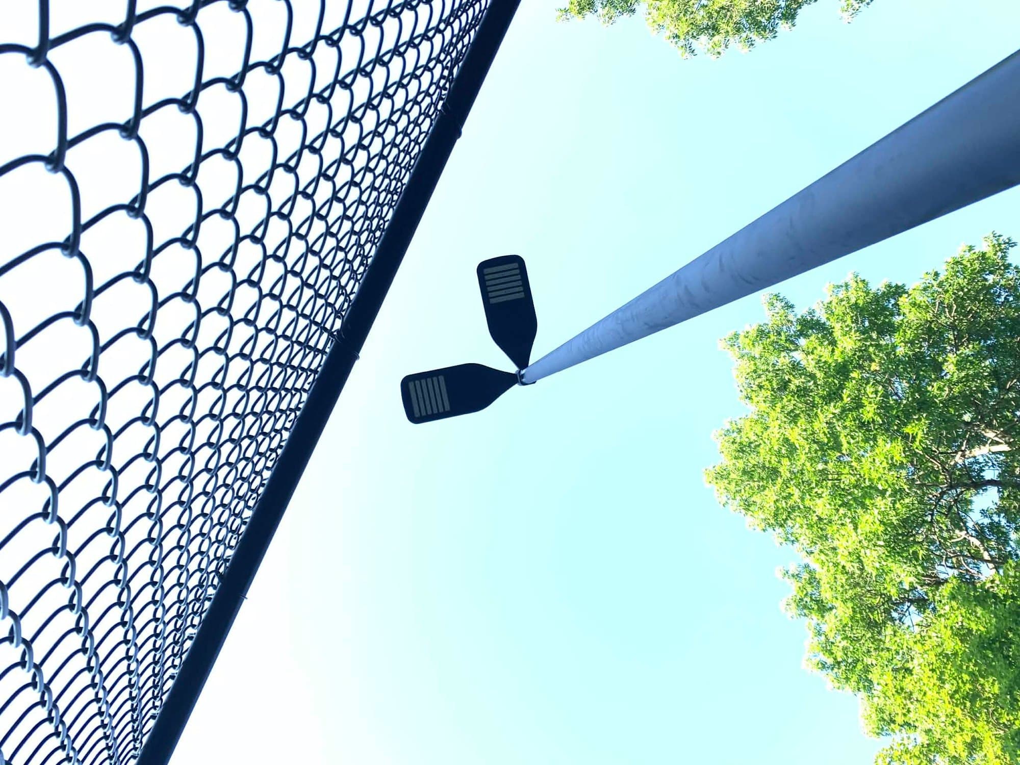 Pole with two LED floodlights near a fenced field