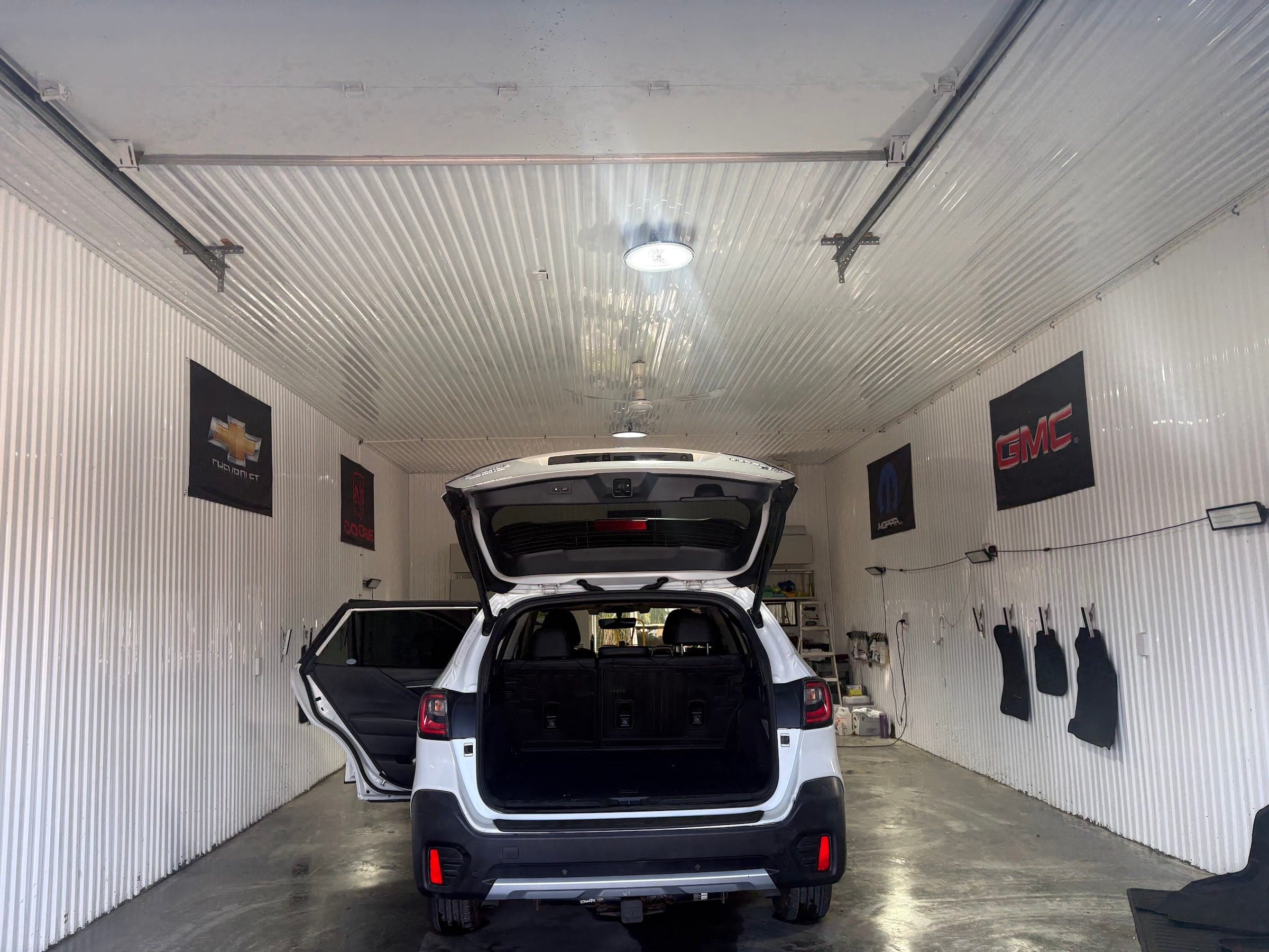 Garage éclairé avec luminaires au plafond, véhicule en entretien